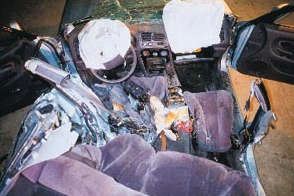 A view from the rear of the Mitsubishi Galant involved in the Dayton, OH incident, looking forward, shows crush damage on the driver's side. The victim being worked on had his feet crushed in the reat footwell area behind the driver's seat. The airbag diagnostic unit is on the driveshaft hump to the left of the passenger's seat.