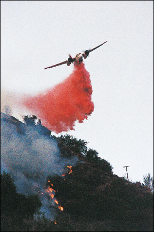 Fixed-wing aircraft joined in the attack on the fire. Here, a California Department of Forestry & Fire Protection (CDF) S-2 drops retardant on the fire line near the end of daylight on the first day of the incident.