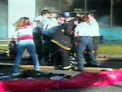 Personnel attend to firefighter on stretcher at scene. Personnel attend to firefighter on stretcher at scene.