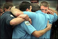 Firefighters and other emergency services personnel share their grief Sunday before a procession for three Coos Bay firefighters.