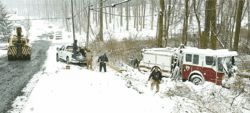 Braddock Heights volunteer firefighters remove equipment from Engine 121 on Sunday afternoon as a large tow truck stands by to pull the fire engine from woods. The vehicle overturned on Swimming Pool Road and rolled into the woods, ending up on its wheels, while trying to avoid two stranded cars. One person was struck by the fire engine and seriously injured.
