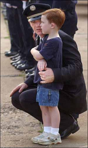 Memphis firefighter Tim Bottom comforts his son Ethan as the funeral procession passes in front of Station 27.