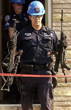Cops retrieve weapons from a burned-out apartment yesterday. Cops retrieve weapons from a burned-out apartment yesterday.