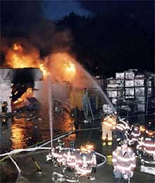 Firefighters battle a blaze at an Oceanside, L.I., cleaning plant yesterday morning after propane and acetylene tanks exploded.