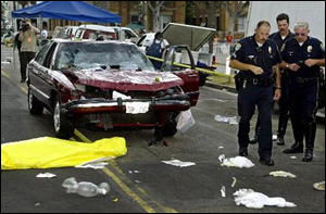 Police investigate the scene near where a body of a victim lies in front of a car that plowed through a crowded farmers market in Santa Monica, Calif., Wednesday, July 16, 2003. According to officials, at least eight people were killed and dozens injured when the vehicle sped through the popular pedestrian promenade