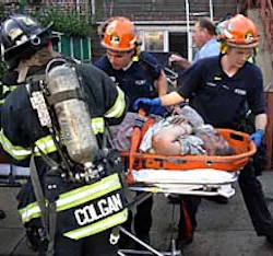 Firefighters rescue a woman, 75, from a house that exploded in flames yesterday. A neighbor kicked in the windows to help. Firefighters rescue a woman, 75, from a house that exploded in flames yesterday. A neighbor kicked in the windows to help.