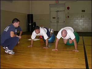 It is harder than it looks! Captain Mark Davis and Lieutenant Chuck Bartlett work more of their abdominal cores by balancing their legs on large exercise balls and then attempting to bring their knees to their chests.