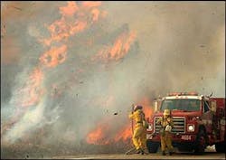 Firefighters stretch hose toward a flare-up in the brush fire near Big Bear, California, a mountain town which has been evacuated and which lies in the path of advancing wildfires, on Wednesday, 29 October 2003. Most businesses and homes have been abandoned and, although firefighters say they hope to protect the town, the fires are out of control and the wind has picked up again. At least 20 people including a fireman have been killed in bush fires that have scorched more than 2,470 square kilometers (950 square miles) of California, officials said Wednesday.