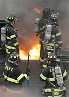 HORROR SHOW: Firefighters look down from a rooftop at the raging fire next door.