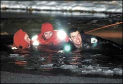 Shawnee Township firefighter Bill McCullough (left) and patrolmen Shane Hartman (cen-ter) and Chris Miracle (right) struggle to pull a man from his submerged car Saturday night. Two people were pulled from the car after it plunged into a pond on Bel-Aire Place near Won-derlick Road.