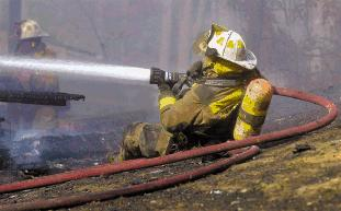 A firefighter hoses down a blaze in Spotsylvania. The county's fire service faces some of the problems noted in a statewide survey