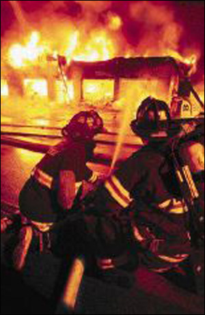 Jeff Scala, left, with the Roosevelt Fire Department in Hyde Park, directs water Tuesday night into the Sound on Wheels business.