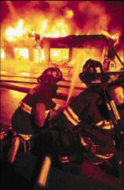 Jeff Scala, left, with the Roosevelt Fire Department in Hyde Park, directs water Tuesday night into the Sound on Wheels business.