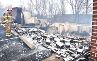 Norman Dudson, with the Sophia Area Fire Department, looks over the remains of the Hilltop Baptist Church, which was destroyed by fire early Monday morning.