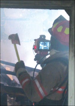 A thermal imager is assisting firefighters in overhaul by identifying hot spots.