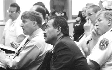 (Far left) Michael J. Weiner, president of the Community Volunteer Fire Rescue Association, (front) Gordon A. Aoyagi, the county's fire administrator, and (far right) Thomas W. Carr Jr., who supervises the county's career firefighters, are among those listening intently as the County Council debates the reform bill that will put all career and volunteer fire and rescue personnel under a single administrator
