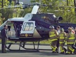 Round Lake volunteer firefighters and other rescue workers carry an injured man from the explosion to a helicopter on Monday, May 17, at Malta Commons