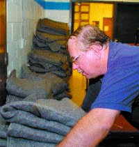 Volunteer John Brown stacks blankets issued by the Red Cross in the hallway of Heritage High School Wednesday morning. &ldquo;I&rsquo;m doing whatever needs to be done,&rdquo; he said.