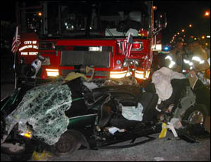 Firefighters at the scene of a crash Sunday that left two men dead and one critically injured when their car ran into the path of a fire truck.