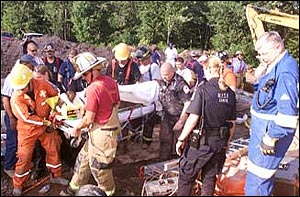 Rescue workers carry Carl Williams, 20, of Monticello, to an ambulance after extracting him from a ditch where he had been trapped for nearly four hours. Williams was working in the drainage ditch for a renovation project at Bethlehem Temple Church on Fairgrounds Road.