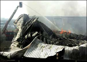 A firefighter hoses down the smoldering remains of a collapsed building after a gas pipeline exploded in the industrial zone of Ghislenghien, some 20 miles southeast of Brussels.