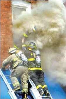 Wood River firefighter's leg sticks through the smoke Tuesday as he dives head-first through the second-story window of a boarding house called Teresa's Inn in Wood River in an attempt to rescue a trapped man who had been standing near the window.