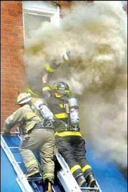 Wood River firefighter&apos;s leg sticks through the smoke Tuesday as he dives head-first through the second-story window of a boarding house called Teresa&apos;s Inn in Wood River in an attempt to rescue a trapped man who had been standing near the window.