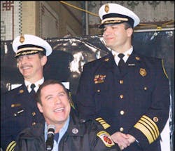 Travolta gives some accolades to the job firefighters do as Baltimore Fire Chief William Goodwin (top right) looks on at the film&apos;s announcement in 2003.