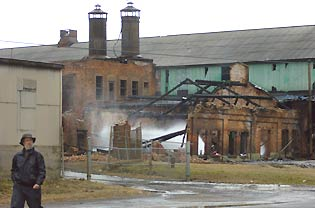 Miles Blakeborough of the Mount Ida Preservation Association walks past the smoking remains of an indutrial building in Troy.
