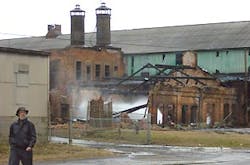 Miles Blakeborough of the Mount Ida Preservation Association walks past the smoking remains of an indutrial building in Troy. Miles Blakeborough of the Mount Ida Preservation Association walks past the smoking remains of an indutrial building in Troy.