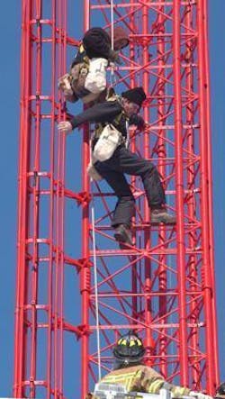 Alan Cook swings away from the tower as co-worker Mike Norman helps lower him to waiting firefighters. The men still were nearly 100 feet off the ground.