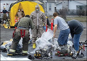 Yakima County Fire District firefighters remove and bag their gear before entering a decontamination tent in Grandview, Wash., Wednesday afternoon, Jan. 26, 2005. A burning warehouse containing farm chemicals at Wilbur-Ellis Co. sent contaminated smoke into the foggy air, prompting authorities to evacuate nearby homes and businesses.