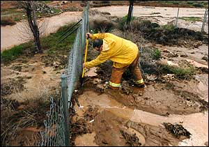 San Bernardino County firefighter Mike Frieling attempts to dig a channel to divert rainwater back into a wash to protect a home in Hesperia, Calif., Monday, Feb. 21 2005. Flood waters made it into the home and the homeowners evactuated.
