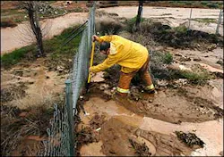 San Bernardino County firefighter Mike Frieling attempts to dig a channel to divert rainwater back into a wash to protect a home in Hesperia, Calif., Monday, Feb. 21 2005. Flood waters made it into the home and the homeowners evactuated.