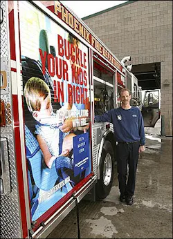 Phoenix Fire Captain Tony Mure of Station 30 shows off an ad on a fire engine in Phoenix, Ariz.. Wednesday, Feb. 16, 2005. Phoenix firefighters have turned 10 of their trucks into rolling billboards, carrying public-safety messages about watching children around water and buckling up.