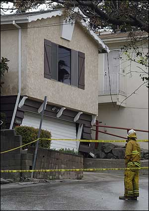 A Los Angeles County firefighter checks the damages to a home red tagged because of unstable ground due to heavy rains in the Glassell Park area of Los Angeles, Wednesday, Feb. 23, 2005.