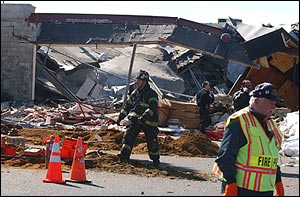 A firefighter walks past the collapsed roof of the PETCO store Friday, March 4, 2005, in Eatontown, N.J., after a damaged gas line exploded, trapping at least four people and scores of animals in the rubble, authorities said.