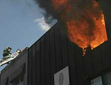 INFERNO: Firefighters scramble to contain an apartment fire in Brooklyn yesterday. The fire was started by a tenant's votive candle that pore Jesus' picture.