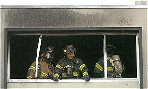 A firefighter peers from a window from the third floor of an apartment complex during a six-alarm fire in San Jose, Calif.