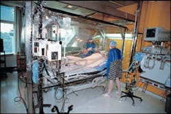 Two nurses assigned to the Acute Floor tend to a patient in the Bacterial Control Bursing Unit, which cares for children with large-percent burn injuries.