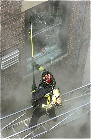 GAS EXPLOSION: A Boston firefighter stands on an elevated ladder as he breaks a window in a building in Boston's Fenway neighborhood Wednesday, April 6, 2005. Seven people suffered minor injuries when an apparent gas explosion heavily damaged the rear of the Northeastern University dormitory, authorities said. (AP Photo/Steven Senne)