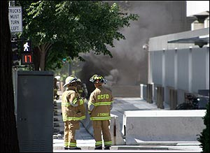Washington firefighters look on toward billowing smoke outside the World Bank in Washington, Thursday, May 26, 2005 after a transformer explosion near the bank. Buildings were evacuated in the World Bank area after the explosion. (AP Photo/Lauren Victoria Burke)