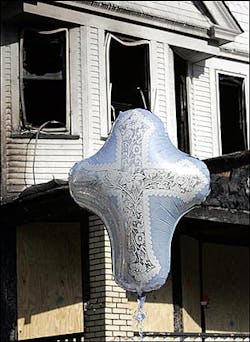 A ballon shaped as a cross floats in front of a burned out house Wednesday, June 1, 2005 in Cleveland. (AP Photo/Tony Dejak)