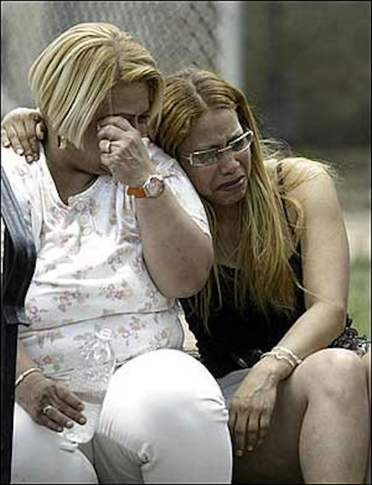 Two unidentified women react after arriving on the scene of a rowhouse fire in the Kensington section of Philadelphia, Sunday, June 12, 2005.