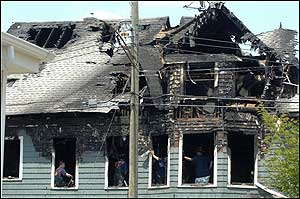 Bridgeport Fire Department officials investigate fire damage to multi-famil home Monday, June 13, 2005, in Bridgeport, Conn. The fire gutted the second and third floors of the wood-frame house, and took two hours to bring under control. Firefighters were able to rescue several residents from the home.