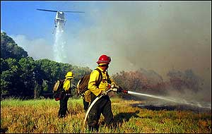 A helicopter makes a water drop on a fire in Morongo Valley, Calif., Wednesday, June 22, 2005, as U.S. Forest Service firefighters work the fire from the ground. The fire has burned at least seven homes.