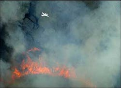 An observation plane flies through the dense smoke above the flames of the Buck Fire on Wednesday June 29, 2005, near Buckeye, Ariz. The brush fire charred up to 400 acres in the Gila River bed before firefighters gained control by Wednesday night.