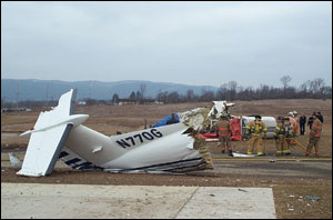 Firefighters from the Bellefonte Fire Department stand by with a handline as officials from the Centre County Coroner&rsquo;s Office and FAA representatives examine the wreckage.