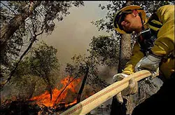 U.S. Forest Service Firefighter Michael Hoon pulls hose while fighting a wildfire in the Barton Flat area of the San Bernardino National Forest, Calif., Tuesday, July 5, 2005. U.S. Forest Service Firefighter Michael Hoon pulls hose while fighting a wildfire in the Barton Flat area of the San Bernardino National Forest, Calif., Tuesday, July 5, 2005.
