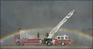 A rainbow forms in the spray from a nearby aerial snorkle truck Wednesday, July 20, 2005, over a Kansas City Fire Department truck at the scene of a four-alarm fire at ABC Tire in the West Bottoms of Kansas City, Mo.